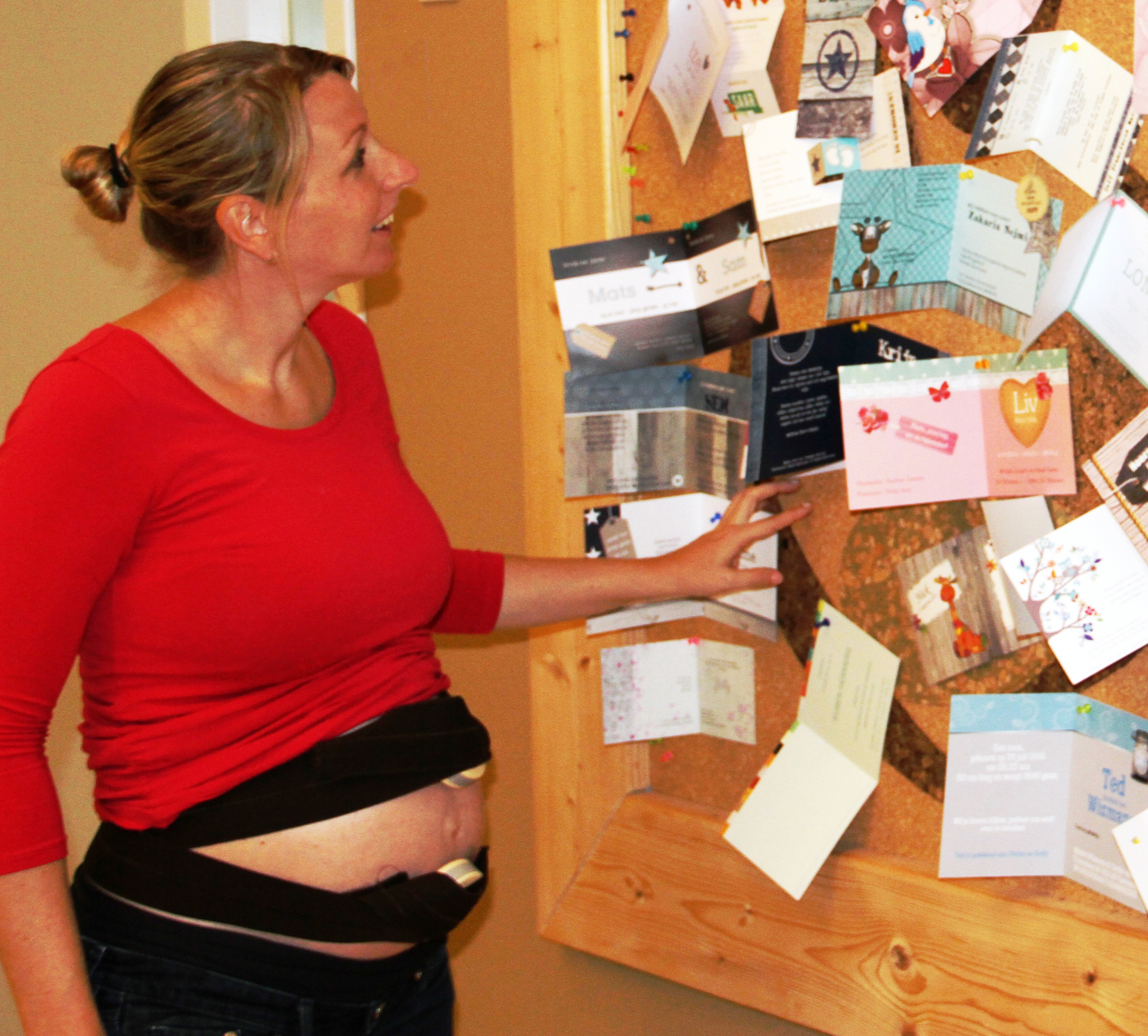 Kraamvrouw kijkt naar bord met geboortekaartjes